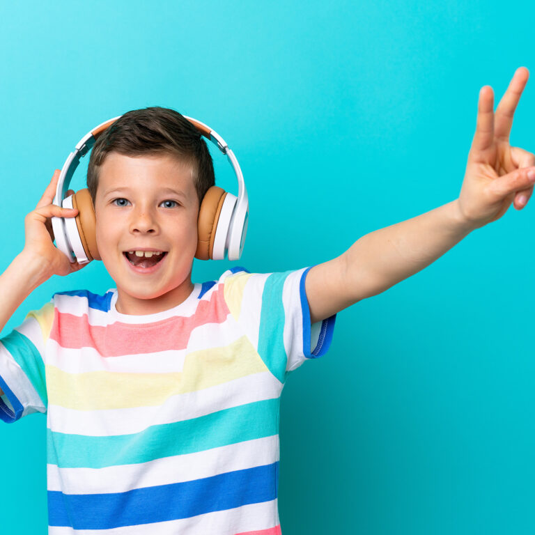 Little boy isolated on blue background listening music and singing