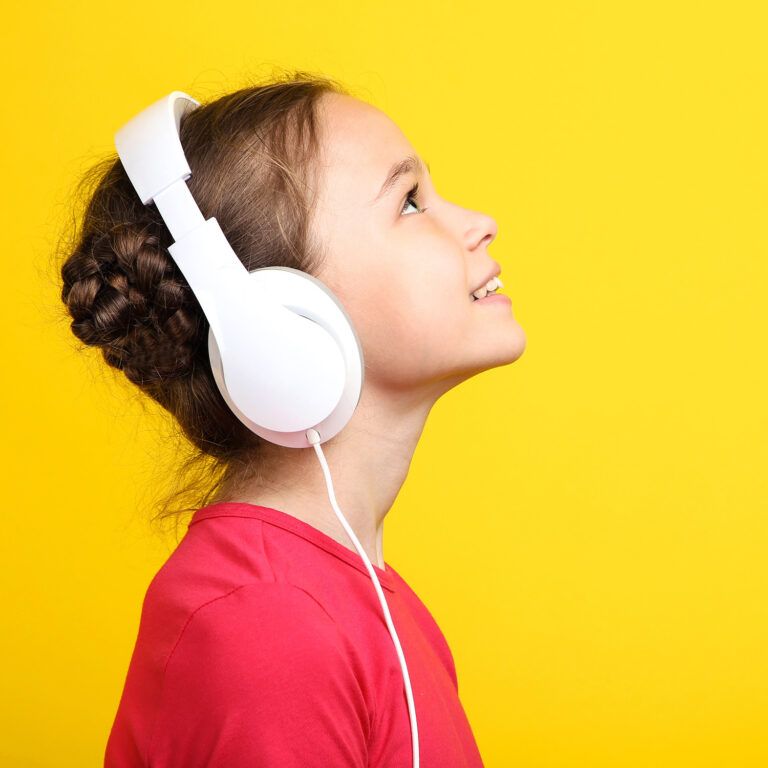 Young girl with headphones on yellow background